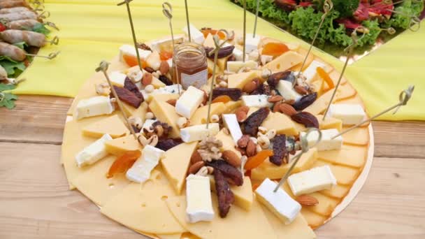 Snacks from hard cheese and dried fruits on large plate close up — Stock Video