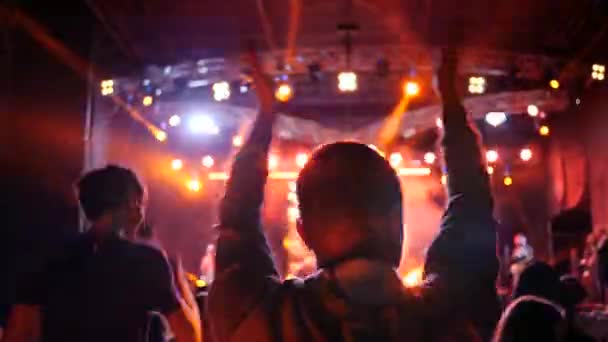 Ventiladores aplauden en concierto iluminado por reflectores en movimiento acelerado — Vídeo de stock