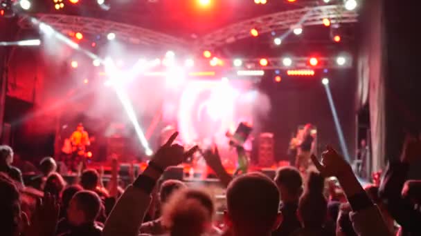 A felemelt karokkal ugráló rajongók élvezhetik az élő zenét a rock koncert alatt éjszaka — Stock videók