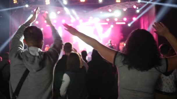Amis applaudissent avec les bras levés avec plaisir sur le festival sur fond de scène éclairée par des projecteurs — Video