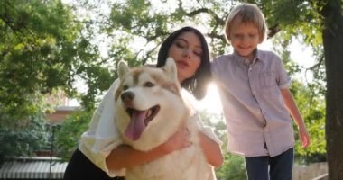 Aile ve evcil hayvan. Doğa ve çocuğun arka planında boğuk köpeğe sarılan kadın.