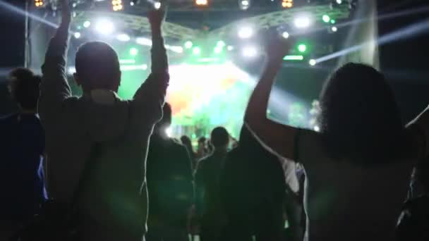 Aktive Fans mit erhobenen Händen klatschen und springen bei Rockkonzert in der Nacht — Stockvideo