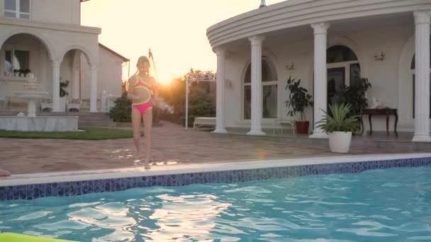 Klein meisje springen in het zwembad, kind sprong met plons in het zwembad, zoete vrouwelijke kind op zomervakantie in de buurt van bekken — Stockvideo