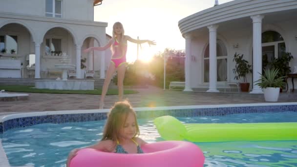 Niña en traje de baño bailando junto a la piscina, dulce niño en anillo inflable nadar en la piscina a la luz del sol , — Vídeos de Stock