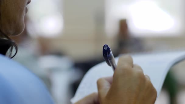 Лекція, крупним планом жінка тримає ручку і шматок паперу в руках — стокове відео