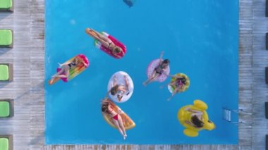 Yaz havuzunda rahatla, neşeli kadın arkadaşlar haftasonu pahalı tatil yerlerindeki havuz kenarında şişme yüzüklerde ve şiltede yüzer.