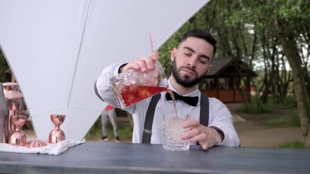 Barägaren häller kyld sprit i glas med is, bartendern förbereder kylande cocktail på bardisken, sommarcafé — Stockvideo