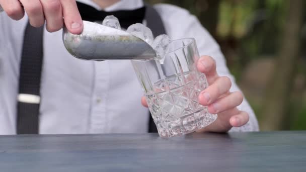 Barkeeper poner cubitos de hielo en vidrio en el mostrador del bar, hombre barman añade cubitos de hielo en vidrio para el alcohol, fiesta de cóctel , — Vídeos de Stock