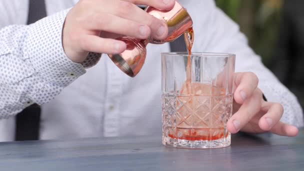 Бармен п'є сік у склянку з льодом на барній стійці, бармен готує охолоджуючий коктейль, вечірка з коктейлем — стокове відео