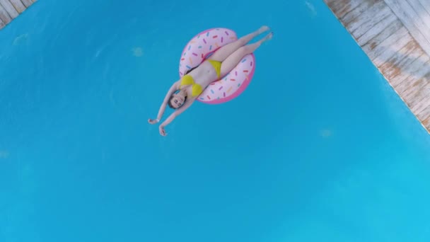 Літній відпочинок, приваблива жінка в купальному костюмі, що плаває на надувному кільці в басейні в дорогому курорті протягом вихідних, вид зверху — стокове відео