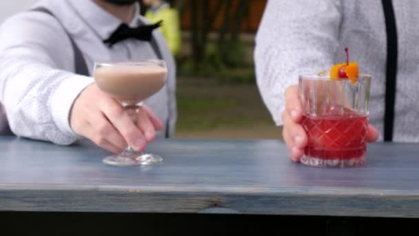 Бармены подают алкоголь, крупным планом, бармен украшенные цветные напитки на барной стойке, в руках барменов охлажденные напитки — стоковое видео