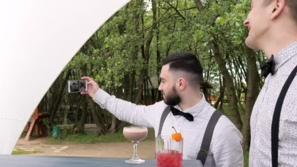 Foto en el teléfono móvil en el lugar de trabajo, camarero hace selfies, alcohol detrás de la barra, bebidas frías de colores en el mostrador de bar , — Vídeos de Stock