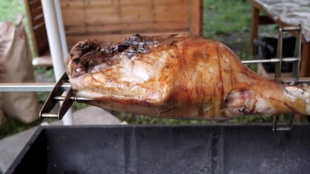 Carne grande pedaço cozido em cuspo, porco assado em uma chama aberta, batons fritos suculentos na grelha de carvão, perna de porco assada na grelha — Vídeo de Stock