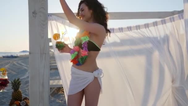 Пляж вечірки, пара на Гаваях має скло, в руках чоловіки і жінки коктейль з фруктами, друзі з яскравими вінками, молоді люди п'ють — стокове відео