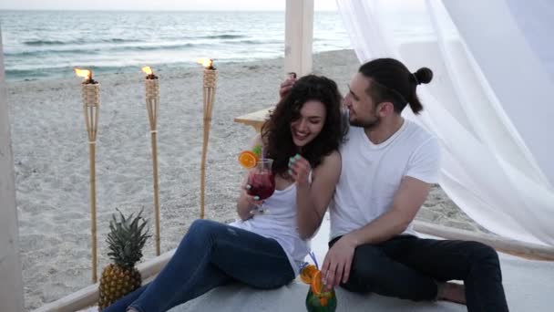 Par kär i cocktails på bungalow ha kul en exotisk semester, på bakgrund tropiska frukter, brinnande facklor — Stockvideo