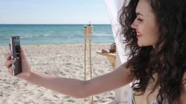Selfphoto Mujer joven en la playa, Teléfono móvil elimina las fotos de vacaciones, chica sonriente Hace selfie en el fondo mar océano y arena , — Vídeo de stock
