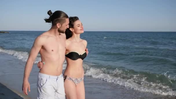 Mann hält Mädchen an der Hand, läuft barfuß auf Sand, verliebtes Paar, ein exotischer Urlaub, im Hintergrund Strandpanorama — Stockvideo