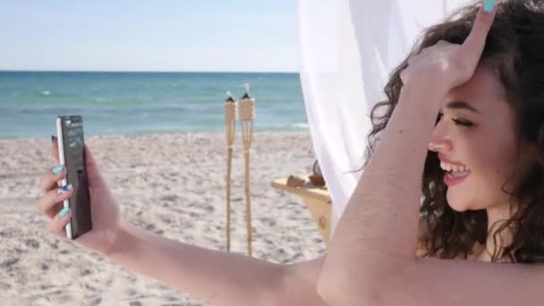 Mosolygós lány Nem szelfi a háttérben tenger óceán és homok, Selfphoto Fiatal nő a strandon, Mobiltelefon eltávolítja nyaralás képek, — Stock videók