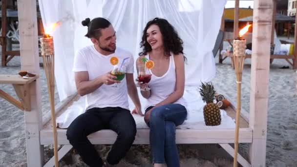 Riposo su spiaggia, coppia amorevole che prende il cocktail in mani, gli uomini e le donne hanno mescolato la bevanda, gli amici con cocktail su tropici, i giovani che bevono — Video Stock