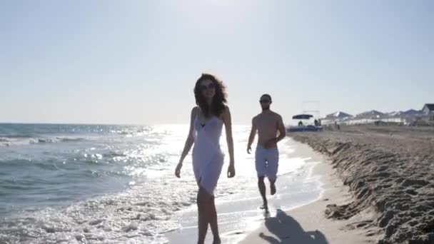 Sommerpause für Liebespaar, positive junge Menschen, die sich umarmen, Meeresküste, glückliche Frau im Badeanzug, am Strand entlang laufend, — Stockvideo