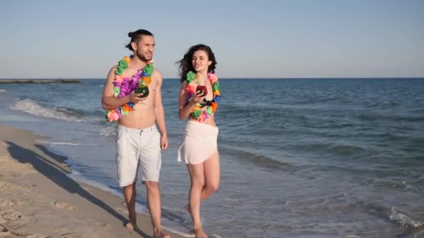 Andando descalço na praia de areia, casal apaixonado beber coquetéis coloridos, viagem romântica havaiana, felicidade as pessoas caminham no resort — Vídeo de Stock