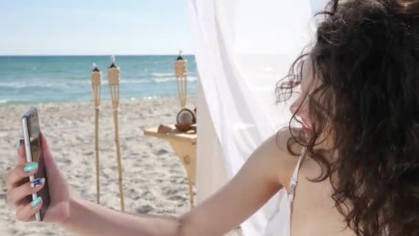 셀피를 복용하고 웃는 여자 해변에서 핸드폰으로 사진을 찍고 여름에 여행하는 모습을 담은 비디오, — 비디오