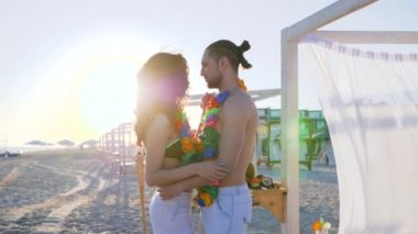 Kumsalda aşıklar, egzotik bir otelde romantik bir dans, erkek kıza elini uzatır ve belinden tutup sahile götürür.,
