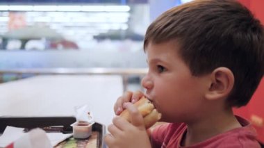 Güzel yemek, çocuk masada zararlı yiyeceklerle oynuyor, Hamburger ve patates kızartması oğlum için, okul kafeteryasında yağlı yiyecekler.