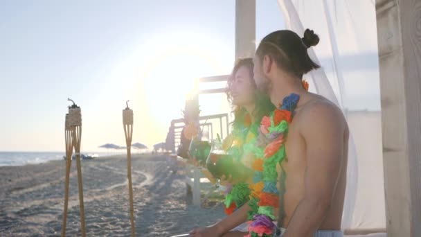 Feminino seu homem aponta mão em distância, lei havaiana no pescoço jovens na costa do oceano, luz de fundo dos raios sóis — Vídeo de Stock