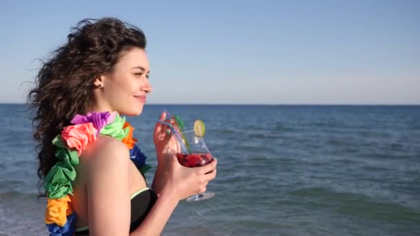 Retrato chica En la playa en verano, las mujeres con hermoso pelo rizado mirando a la cámara en la playa celebración de cóctel, Sexy joven mujer — Vídeos de Stock