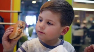 Küçük çocuk çocuk çocuk restoranında iştahla yer, çocuk akşam yemeği yer, patates kızartması ve öğle yemeği için hamburger yer.,