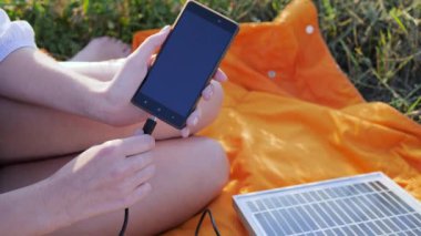Ekran cep telefonunu kapat, kızı güneş panelinden cep telefonuna bağla, genç kadın cep telefonunu şarj et