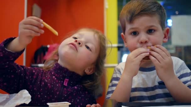 Cheeseburger και τραγανές πατάτες για ελαφρύ μεσημεριανό γεύμα για ενεργά δίδυμα, νόστιμες τηγανητές πατάτες με σάλτσα για μικρό κορίτσι και αγόρι, — Αρχείο Βίντεο