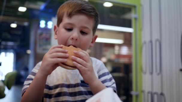 Cibo per bambini a cena, patatine fritte e hamburger a pranzo per scolaro, bambino maschio mangia hamburger e patatine fritte con salsa — Video Stock