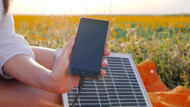 Мобильный телефон, подключенный к солнечным фотоэлектрическим панелям на открытом воздухе, зарядное устройство на солнечной энергии, возобновляемые источники энергии, закрыть — стоковое видео