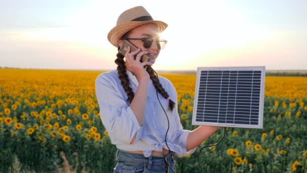 Генерация энергии, женщина говорить телефон и держать солнечную батарею отслеживания солнца для зарядки батареи, девушка говорит по мобильному телефону — стоковое видео