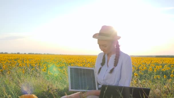 Menina segurar na mão matriz solar e mostra gesto mão como usar o painel ao ar livre, feminino na luz de fundo com carregador de notebook — Vídeo de Stock