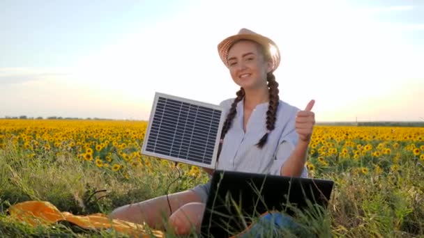 Portret dziewczyna pokazuje aprobatę i trzyma w rękach panel słoneczny na świeżym powietrzu, kobieta w podświetleniu z notebooka ładowarka w ramionach — Wideo stockowe