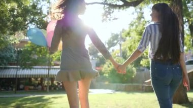 nice female friends with inflatable balloons smiling outdoors, happy emotions in backlight