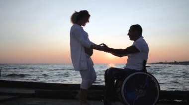 Mutlu engelli bir kadın koca göbekli, tekerlekli sandalyede sakat bir kadını okşar. Karısının deniz kenarındaki karnını dinler.