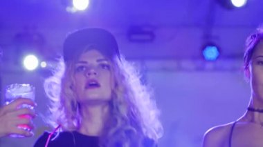 Kokteylle kadeh kaldıran kızlar gece kulübünde eğleniyor, içecekle dans eden kızlar partide kadeh kaldırıyor.