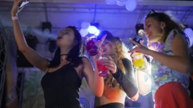 Gece kulübünde parlak bir içki, gece partisinde alkolle dans eden seksi kadınlar, içecekle dans eden kızlar.