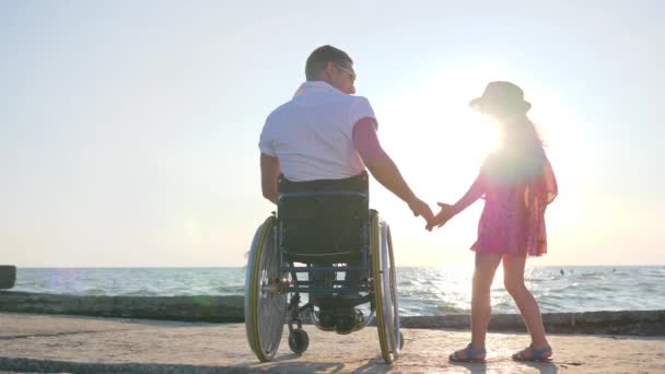 Těhotná dívka udržuje paže zdravotně postižený muž na invalidním vozíku — Stock video