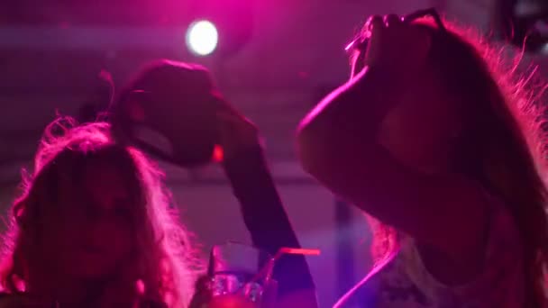 Smiling girlfriends with bright drinks have fun at nightclub, happy women drinking during dancing at night — Stock Video