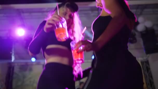 Sexiga tjejer som håller glasögon med cocktails och dansar på nattklubben, vackra kvinnor med dryck på fest i discobelysning — Stockvideo