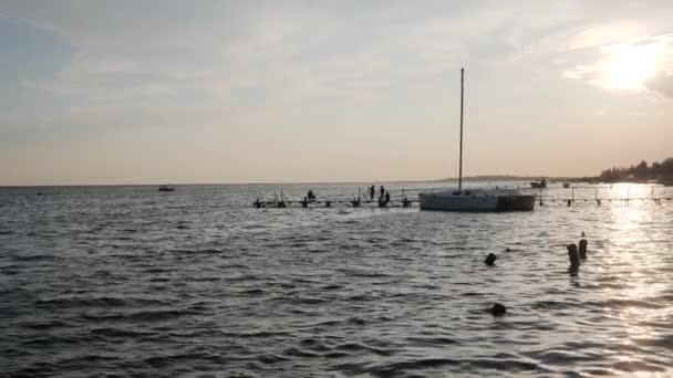 Pôr-do-sol, belo sol nascendo sobre o rio em câmera lenta, pessoas silhuetas na pesca, seres humanos no cais à noite — Vídeo de Stock