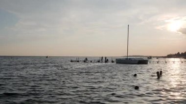 Gün batımlı deniz manzarası, nehrin üzerinde yavaşça yükselen güzel güneş, balık tutan siluet insanlar.