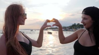 En iyi kız arkadaşlar ellerini arka planda tutar. İki genç kadın gün batımında fotoğraf için poz verir.,