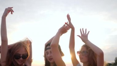 close up faces girlfriends, summer evening, happy best friends dancing in sunset on beach, three female raises arms