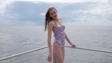 Deniz kıyısında mayo giymiş gülümseyen genç bir kadın Embankment 'a düzgün bir kadınsı vücut, ince bir kız.